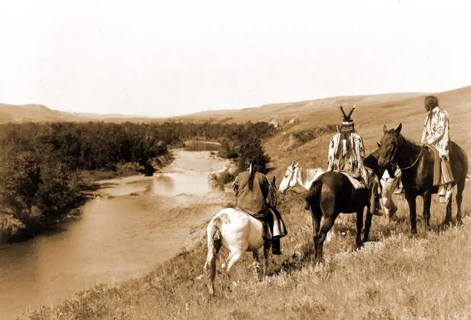 Edward S. Curits Native American Indians - Three Piegan Indians and four horses on hill above river circa 1910.