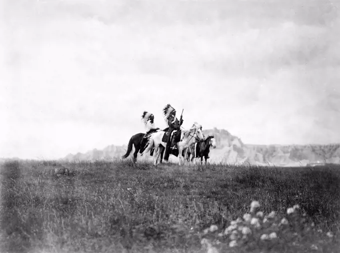 Edward S. Curits Native American Indians - Three Sioux Indians of horseback on plains with rock formation in background circa 1905.