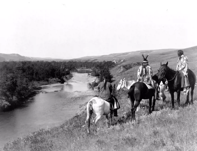 Edward S. Curits Native American Indians - Three Piegan Indians and four horses on hill above river circa 1910.