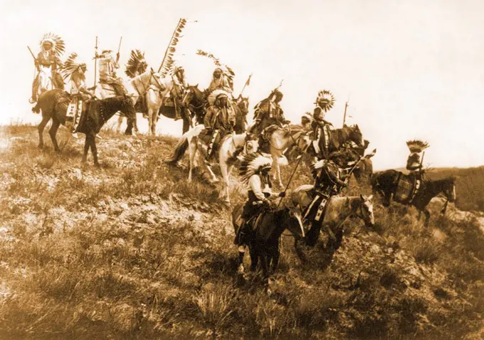 Edward S. Curits Native American Indians - Several Oglala men, many wearing war bonnets, on horseback riding down hill circa 1907.