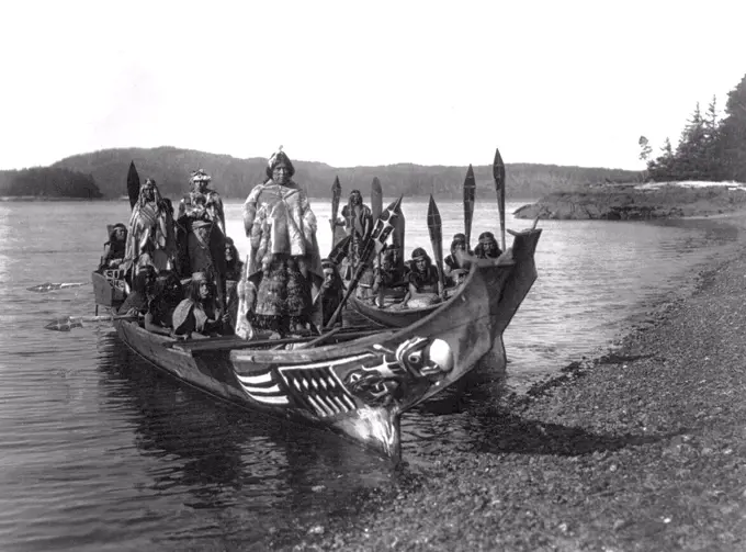 Edward S. Curits Native American Indians - Two canoes pulled ashore with wedding party, bride and groom standing on 'bride's seat' in the stern circa 1914.