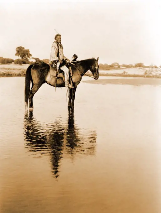 Edward S. Curits Native American Indians - Cheyenne man on horseback in shallow water circa 1927.