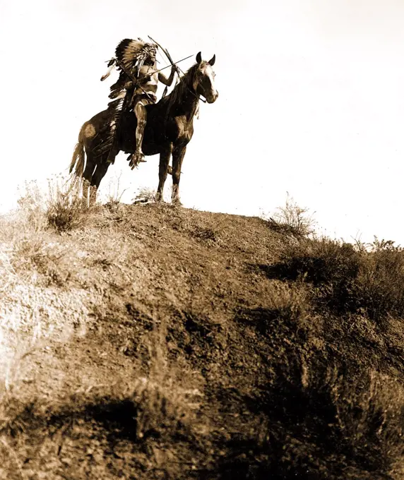 Edward S. Curtis Native American Indians - Indian Man in feather headdress, on horseback, holding bow and arrows circa 1908.