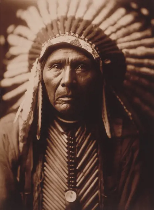 Edward S. Curtis Native American Indians -  Three Horses, head-and-shoulders portrait, facing front, wearing headdress circa 1905.