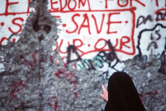  A nun studies the graffiti on a section of the Berlin Wall..