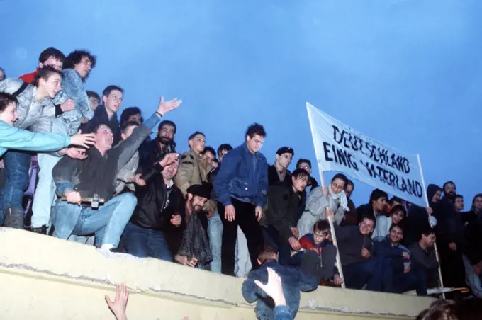  A crowd celebrates atop the Berlin Wall following the official opening of the Brandenburg Gate..