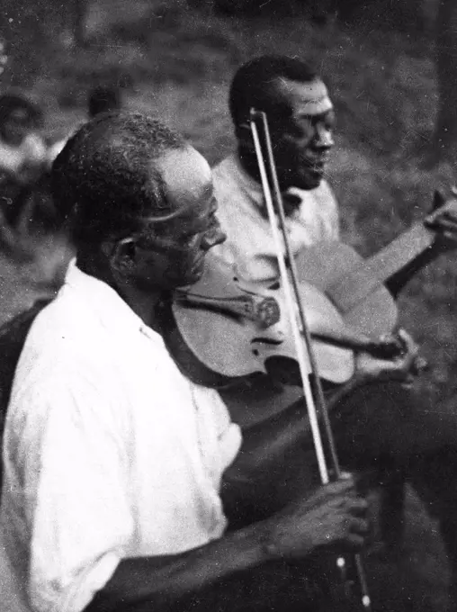 Stavin' Chain playing guitar and singing the ballad 'Batson' accompanied by a musician playing violin, Lafayette, La. circa June 1934.