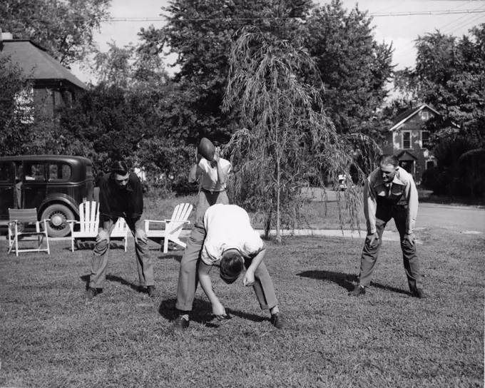 1948 - A father in Arlington, Virginia, Takes Time to Play Football with his Three Sons After Working Hours. 