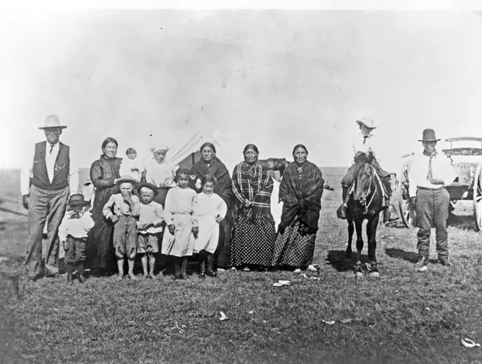 Group of Kickapoo Indians, standing outside tent, dressed in Euro-American clothing ca. 1909.