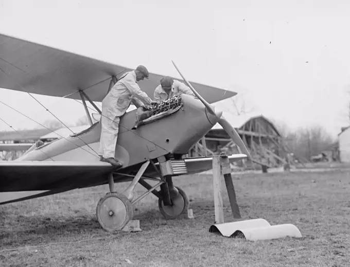 Men examining airplane engine ca. between 1909 and 1923.