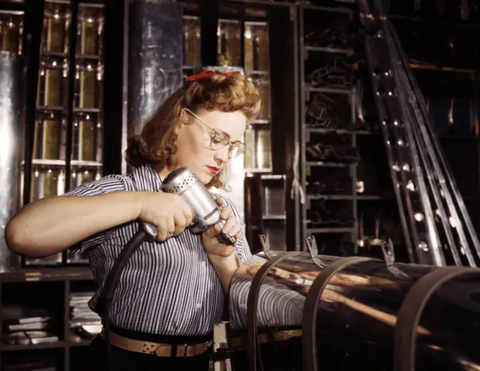 Operating a hand drill at North American Aviation, Inc., a woman is working in the control surface department assembling a section of the leading edge for the horizontal stabilizer of a plane, Inglewood, Calif. - October 1942. 