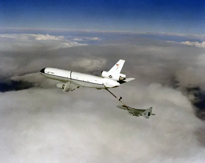 1982 - Air-to-air left side view of a KC-10A Extender aircraft refueling an F-15A Eagle aircraft above the clouds.. 