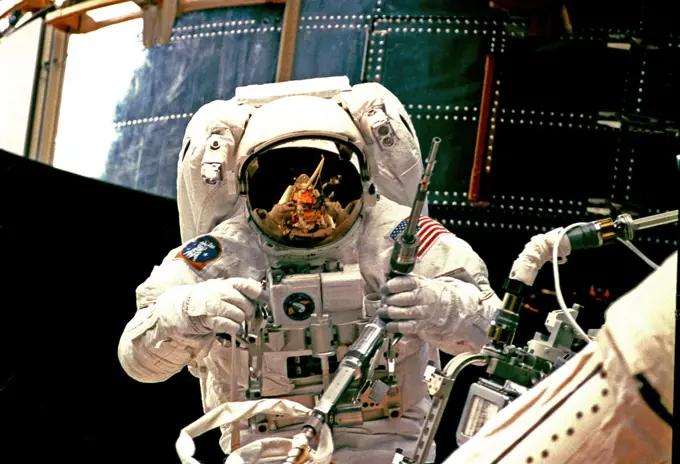 (13 Feb. 1997) --- Astronaut Steven L. Smith picks up a power ratchet tool as he prepares to join astronaut Mark C. Lee (out of frame) on the first space walk of the STS-82 mission to service the Hubble Space Telescope (HST), temporarily latched down in Discoverys cargo bay (background). 