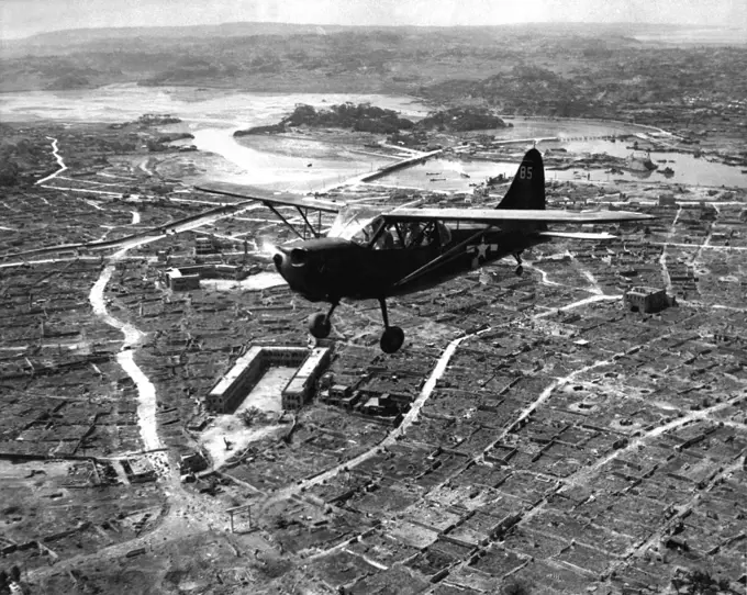 Japan/USA: A U.S. Marine Corps Stinson Sentinel flies over the razed city of Naha, capital of Okinawa. Battle of Okinawa, May 1945