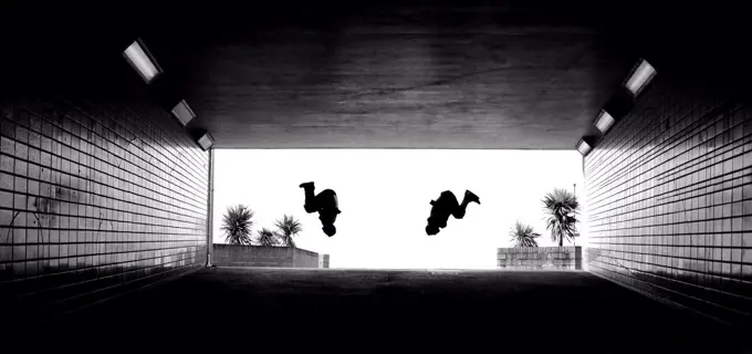 Two parkour athletes perform a backflip.  