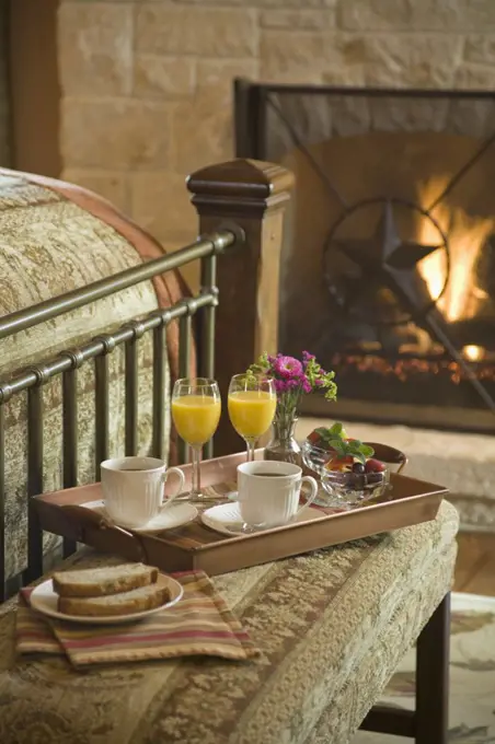 Tray with cups of coffee and orange juice on stool at foot of bed, Texas. 