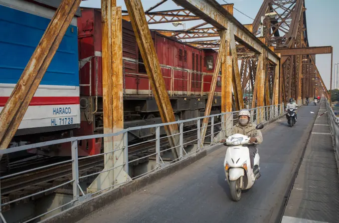 A Vietnam Railways train passes motorcycle traffic on the famous Long Bien bridge, Hanoi, Vietnam.