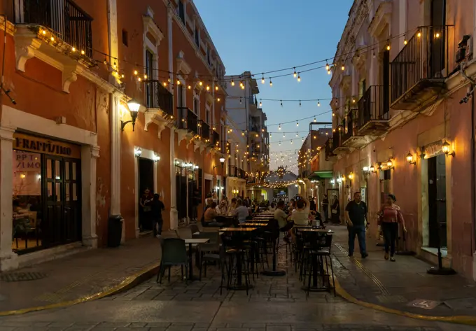 Restaurant tables in street at night with hanging lights, Campeche city, Campeche State, Mexico.