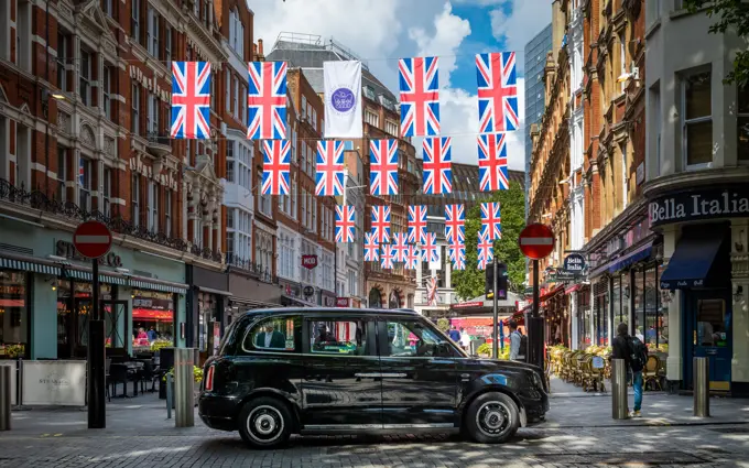 A TX City electric black cab waits for passengers under Jubilee bunting in central London.