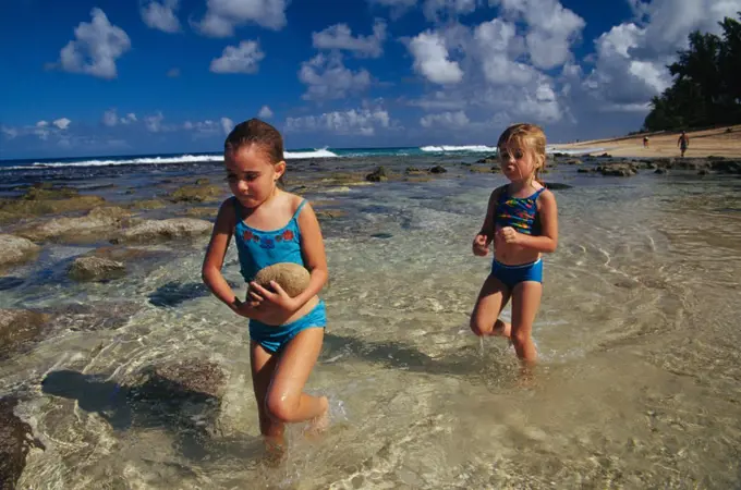 Two Girls (6 And 4) Playing With Rocks In A Tidal Pool On The North Shore Of Oahu, Hawaii.