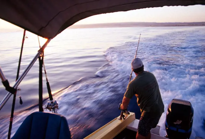 Man Rigging Deep Sea Fishing Poles On Fishing Boat Off The North Shore Of Oahu, Hawaii.