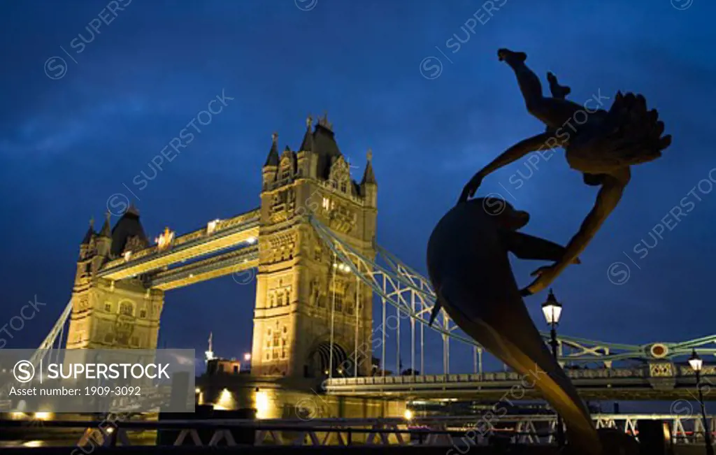 Tower Bridge and Statue Girl with Dolphin illuminated at night London England UK United Kingdom GB Great Britain British Isles