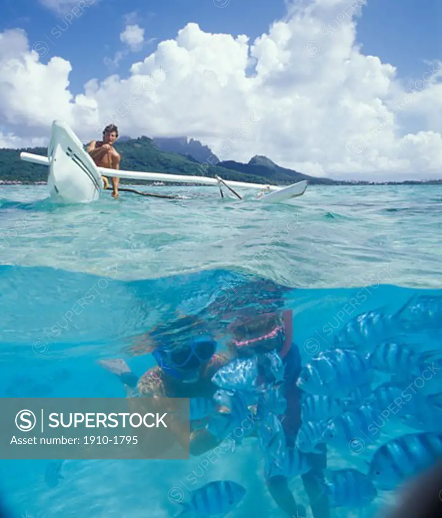 Man paddling outrigger canoe overtop of snorkelers and fish digital composite Outrigger canoes are native to the Polynesian islands where they have been used for centuries TAHITI French Polynesia Bora Bora