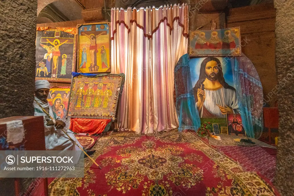 A man sits near a collection of Christian artwork within the church of  Bet Medhane Alem (Church of the World Savior) in Lalibela , Ethiopia