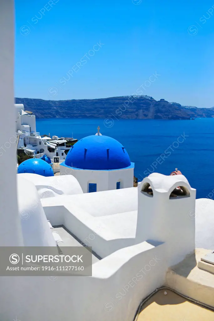 Hillside buildings with traditional church blue domes in Oia, Santorini, Greek Islands, Greece