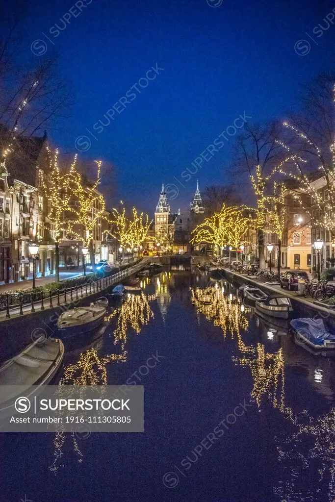 Beautiful lighted trees line the  Amsterdam canal dubbed the "Venice of the North" which leads to Rijksmuseum a Dutch history museum in Amsterdam, Netherlands