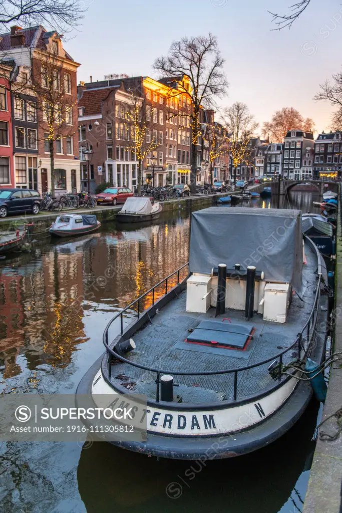 A boat reading "Amsterdam" is docked in a canal in Amsterdam, Netherlands