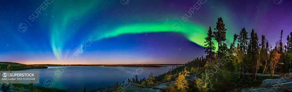 The arc of Northern Lights starting a show in the deep twilight over Prelude Lake on the Ingraham Trail near Yellowknife, NWT. This was September 9, 2019. Light from the waxing gibbous Moon behind the camera also illumimates the scene. The autumn colours make for a good contrast with the sky colours. This was from the lookout point above the lake and main parking area and boat launch. The Big Dipper is at left; Capella is at centre; the Pleiades and Hyades are rising at right of centre. This