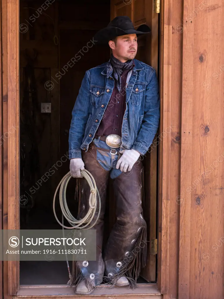 A cowboy wrangler with his lariat on the Red Cliffs Ranch near Moab, Utah.  He wears leather chaps to protect his legs from thorny brush while riding the range.