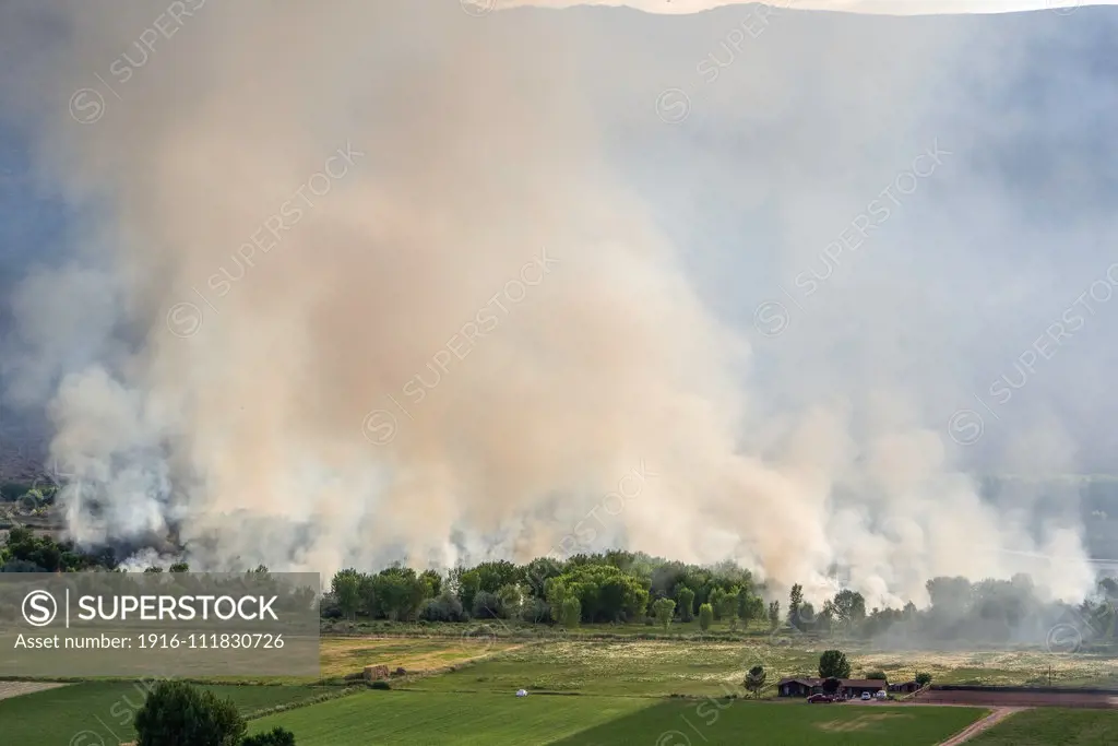 A wildfire burning in The Nature Conservancy Scott M. Matheson Wetlands Reserve near Moab, Utah, threatening a nearby farm.