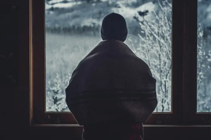 Man looking out of the window into a winter wonderland. Yukon Territory, Canada