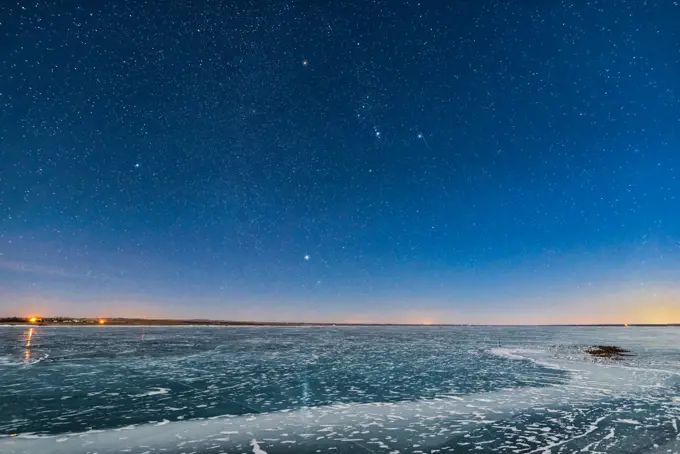 Orion and the Dog Stars (Procyon and Sirius) rising over frozen Lake MacGregor in southern Alberta, on February 2, 2017, on a clear moonlit night, with a 6-day Moon lighting the scene. Note the glitter path reflection of Sirius in the ice. The last of the evening twilight lights the horizon at right. This is with the Sigma 20mm Art lens and Nikon D750.