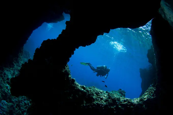 A diver swims past Boo Windows on Boo Island, Raja Ampat, West Papua, Indonesia, Pacific Ocean