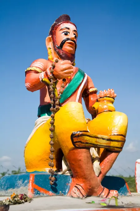 Colourful religious statue depicting man sitting on wall at a Hindu Shrine, Tamil Nadu, India
