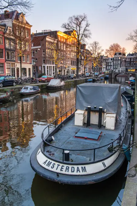 A boat reading "Amsterdam" is docked in a canal in Amsterdam, Netherlands