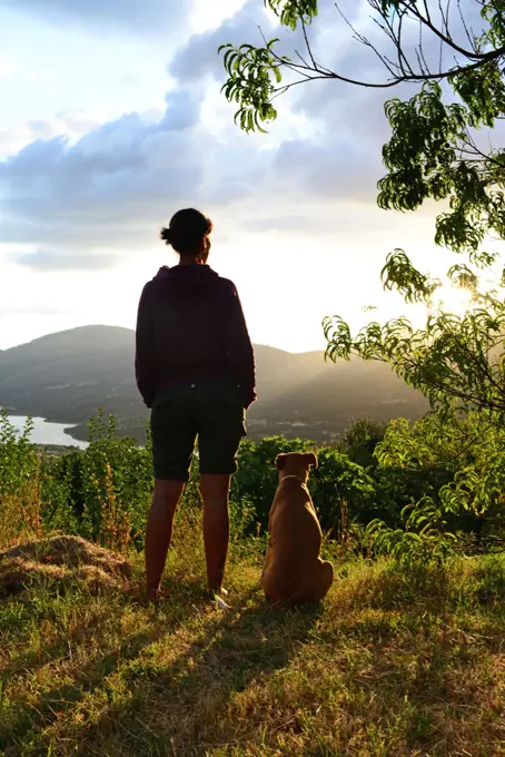 Young woman with her dog at sunset