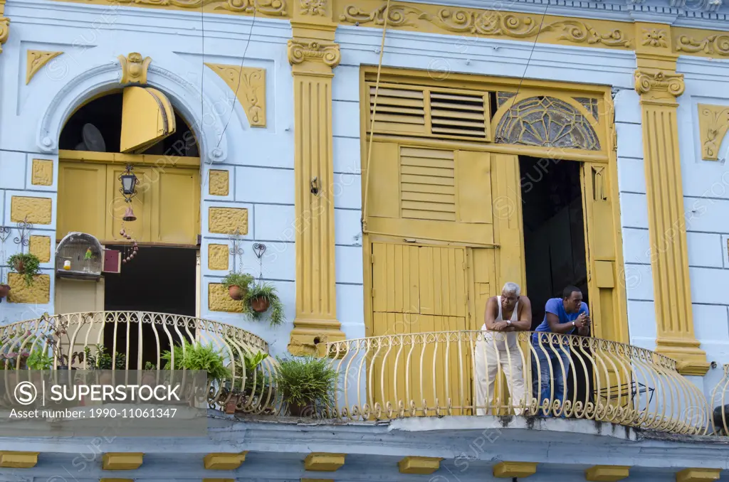 Colorful building facade with men on balcony, in Havana, Cuba