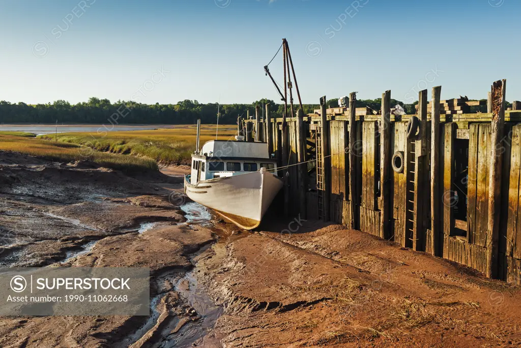 Fishing boat stranded on the mud flats at low tide in Minas Basin. Bay of Fundy. Delhaven, Nova Scotia. Canada.