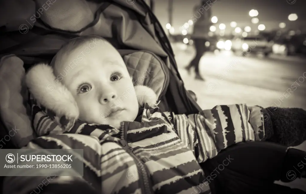 Baby boy in a stroller on the street at night