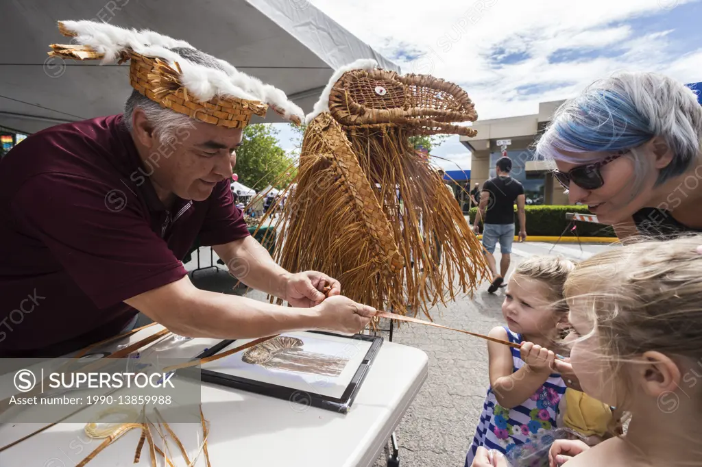 A first nation weaver works with cedar strips and a little help from a young onlooker during Canada Day celebrations held in Campbell River, Campbell ...