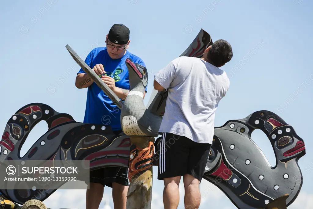 Family members refurbish a mortuary pole at the gravesite of a family member. Campbell River, Vancouver Island, British Columbia, Canada