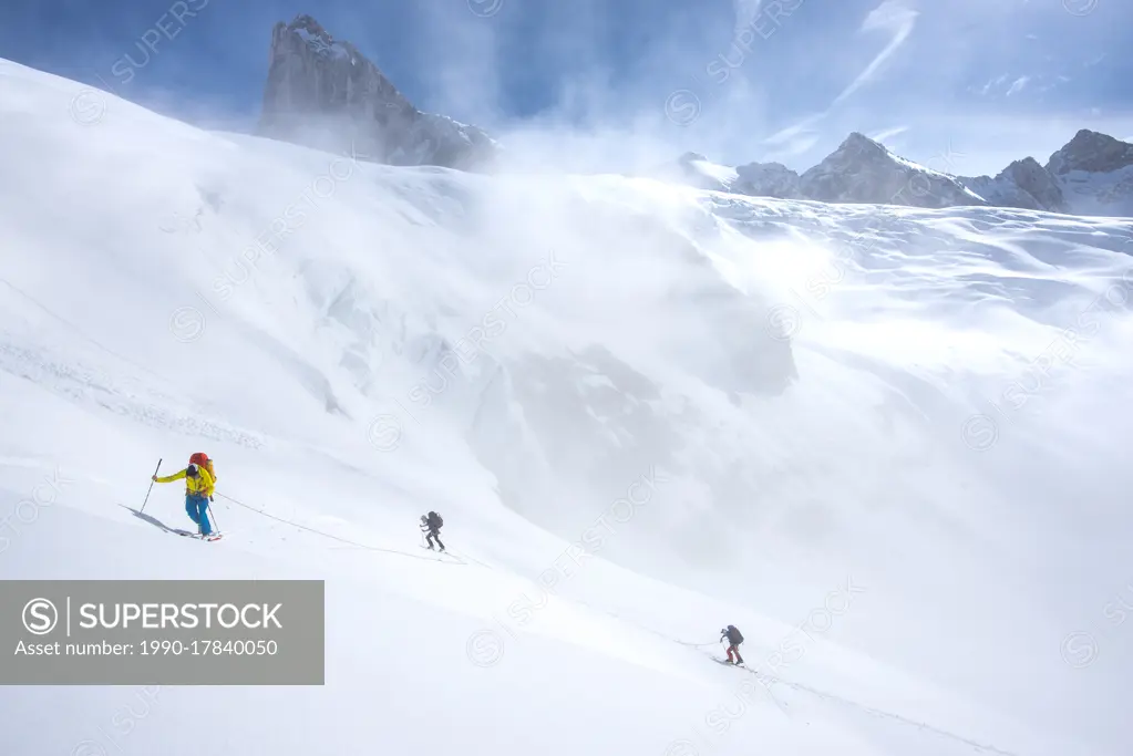 Three backcountry skiers climbing up onto the Conrad Icefield, a major ascent on the first day of the Bugaboos to Rogers Pass ski traverse, British Co...