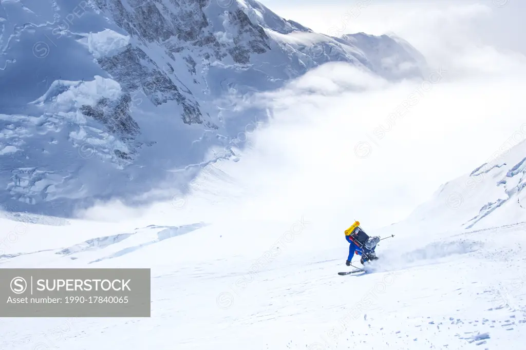 A skier descends the King's Trench route on Yukon's Mount Logan (Canada's highest peak), with King's Peak towering behind.