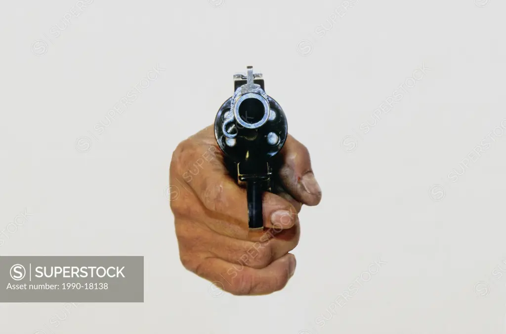 A human hand pointing a loaded revolver frontward.