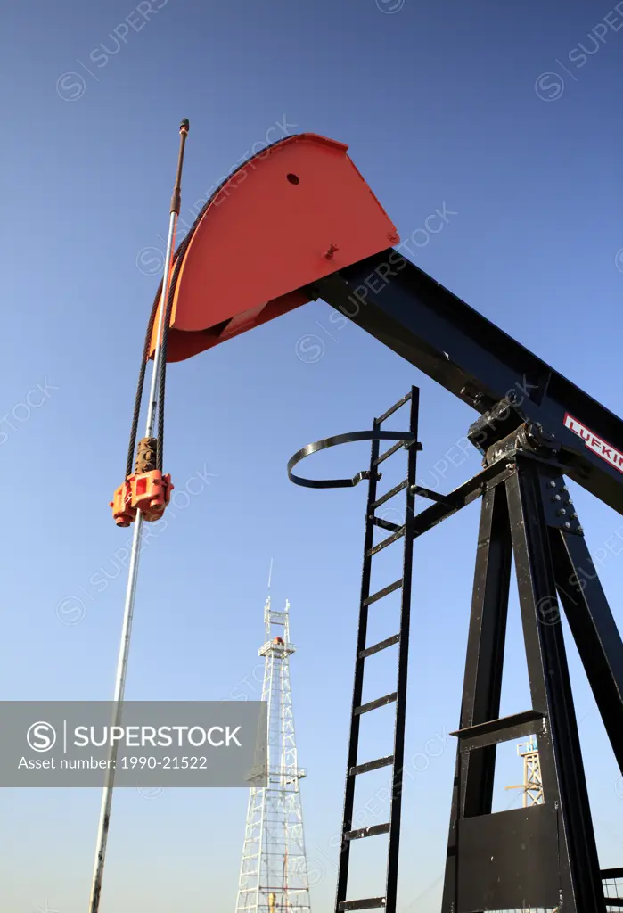 Pump jack with oil drilling rig in background at Canadian Petroleum Discover Museum in Devon, Alberta, Canada.