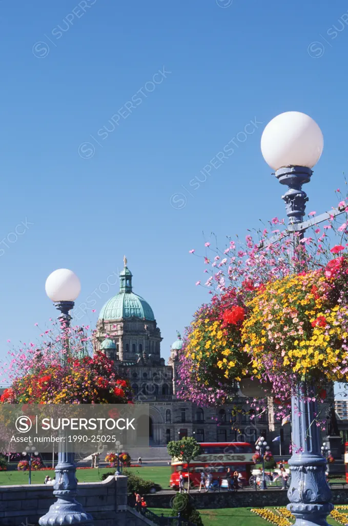 Flower baskets hanging from lamp posts with the Parliament buildings beyond, Victoria, Vancouver Island, British Columbia, Canada